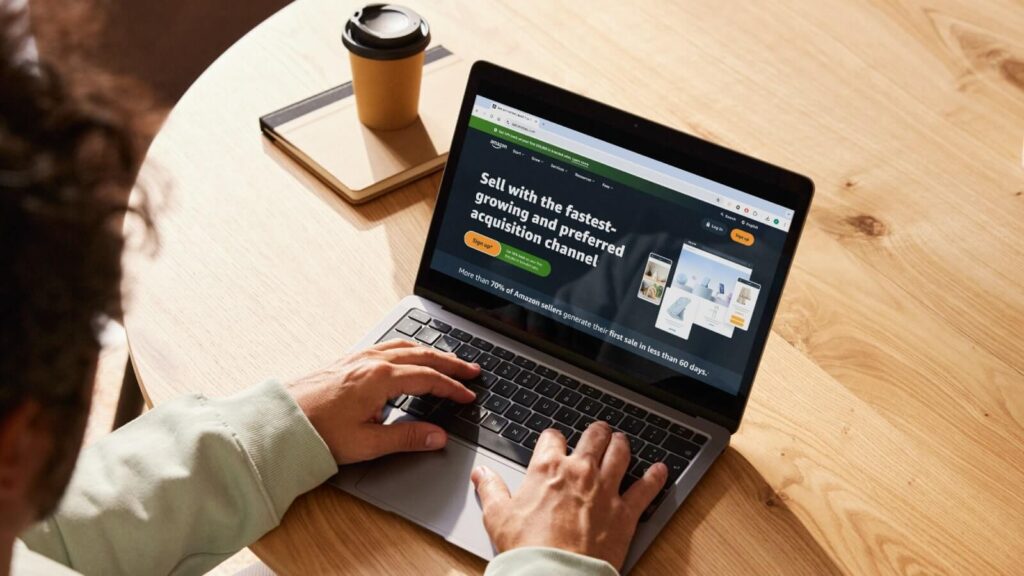 A man sitting at a desk and viewing Amazon’s homepage on his laptop.
