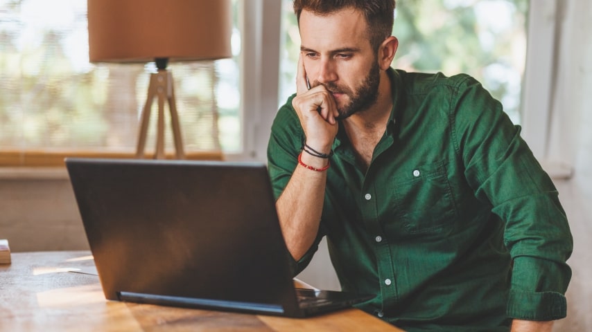 A man looking at a laptop screen and thinking.