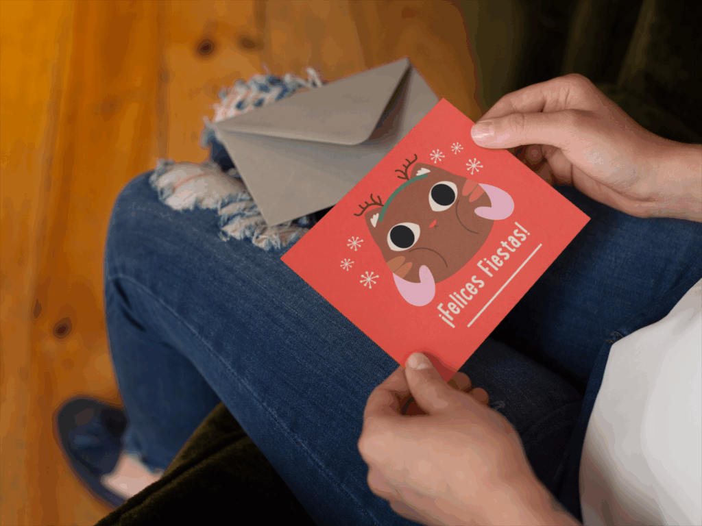 A woman smiles while holding a Christmas card featuring a moose design.