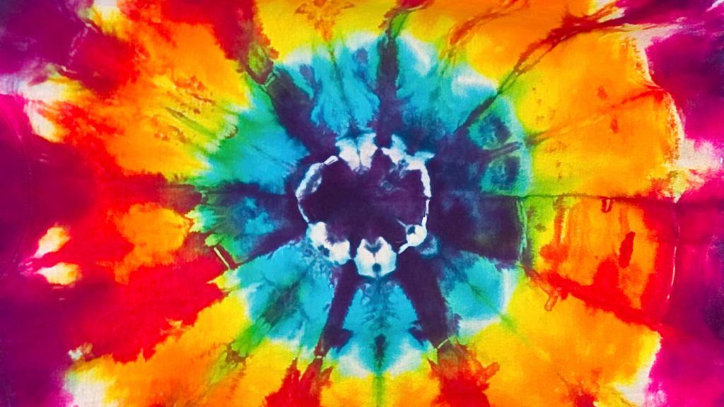 A vibrant tie-dye pattern with a central burst of blue and white, surrounded by rings of red, orange, yellow, and green.