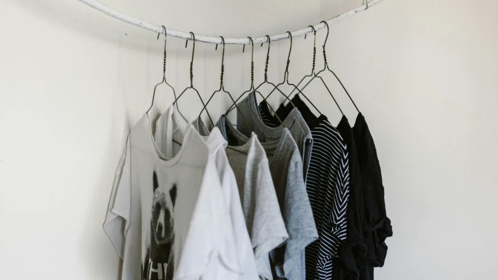 A white wall displaying various clothes neatly hung on hangers.