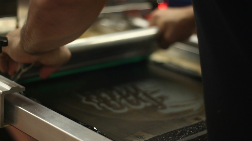 A person using screen printing to create a custom t-shirt.